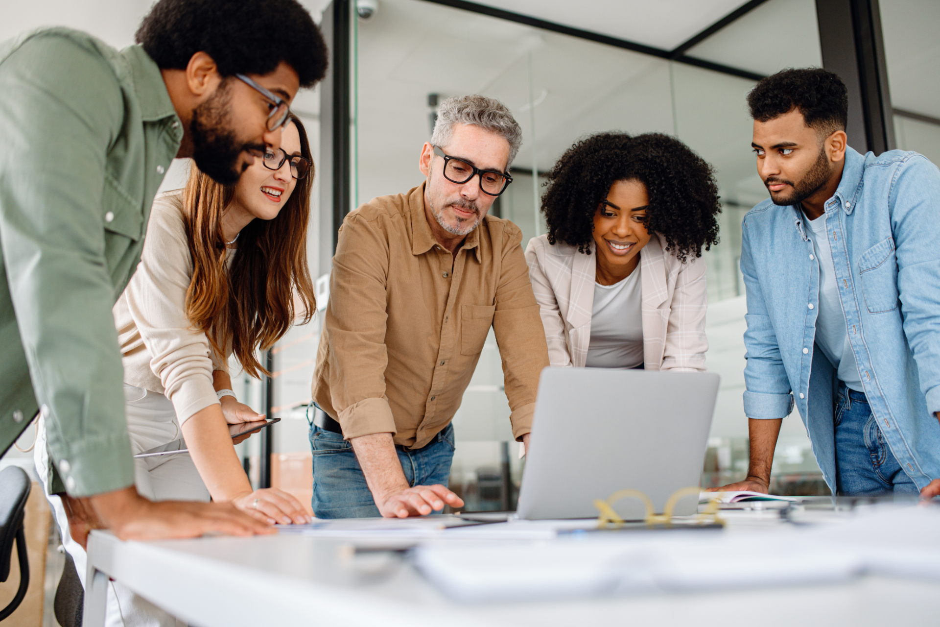 Business professionals reviewing performance charts and analyzing company growth in office environment. Multicultural team working together discussing financial data and planning business strategies