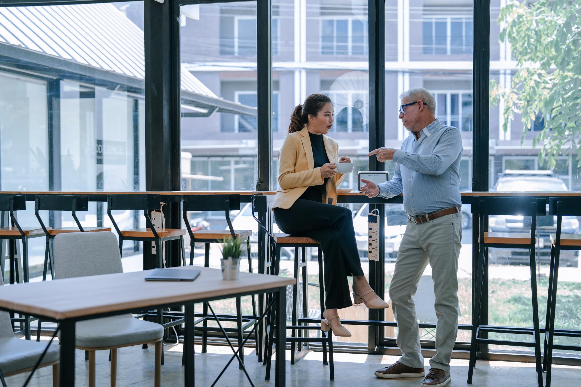 Two businesspeople discussing during a coffee break in a modern office cafeteria