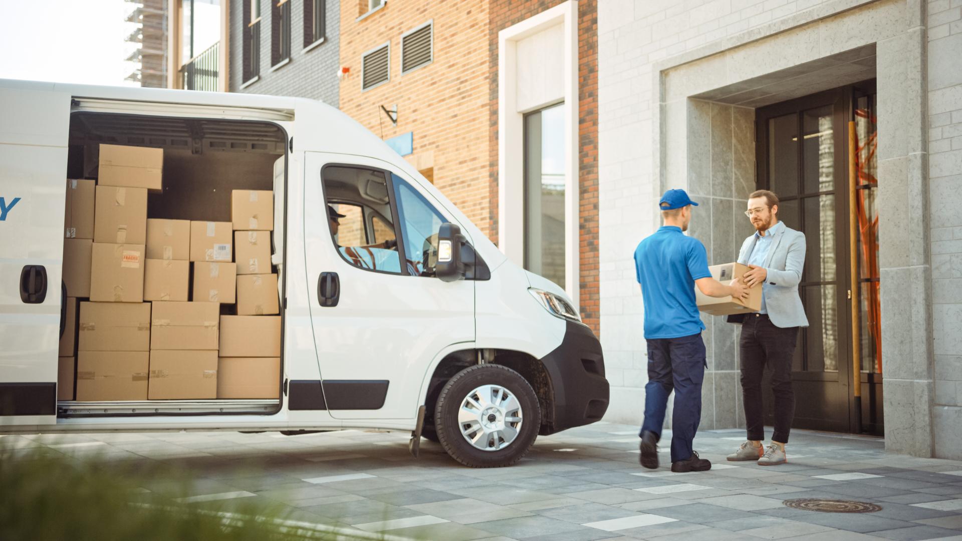 Delivery Man Gives Postal Package to a Business Customer Who Signs Electronic Signature POD Device