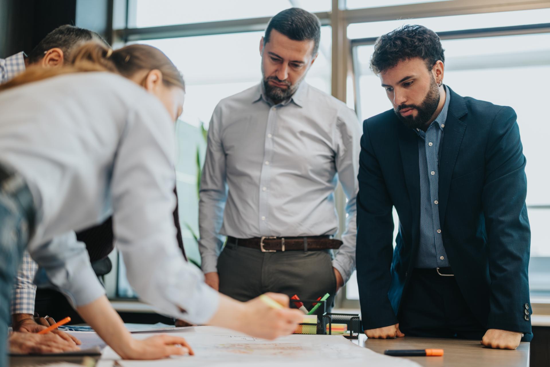 A group of professionals gathers around a table actively participating in a collaborative project or workspace brainstorming session